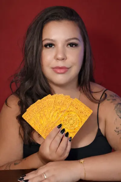 Mariana Rodrigues segurando cartas de tarô douradas